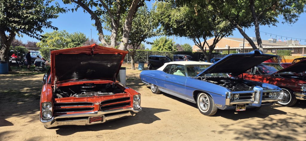 A flamed orange Pontiac and a blue Bonneville convertible with a white top at the 2026 Valley Nationals