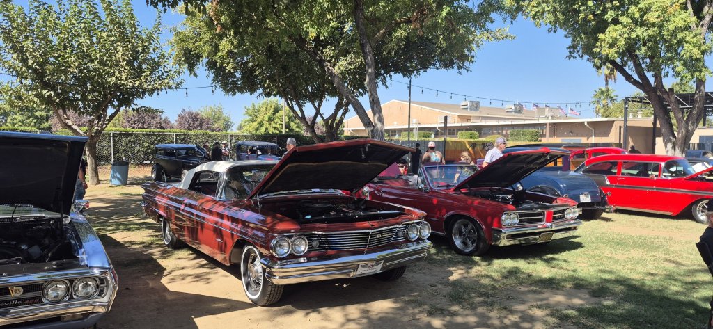 A 1960 Pontiac Bonneville convertible and a red 1964 GTO convertible with their hoods open at the 2026 Valley Nationals